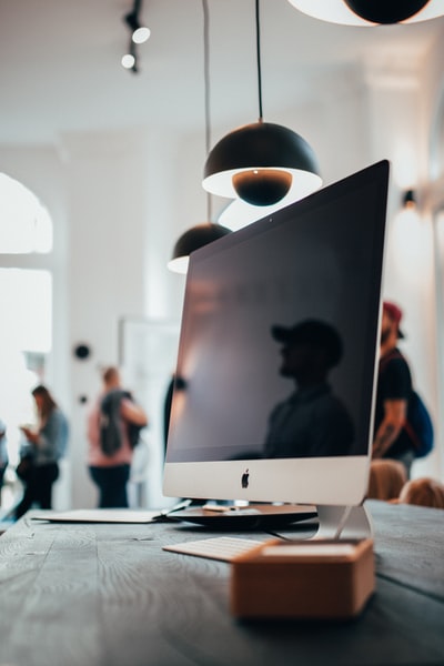 The silver imac that brown wooden table
